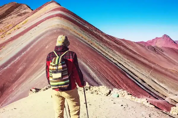 Hiker at the top of the Rainbow Mountain in living the best time to visit Peru