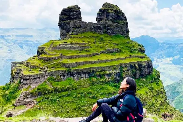 A woman resting after a trekking adventure at an ancient archaeological site in the mountains.